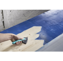 Een persoon gebruikt een verfspreider om verf op hout aan te brengen