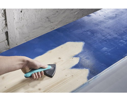 Een persoon gebruikt een verfspreider om verf op hout aan te brengen