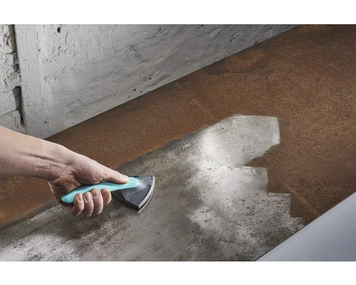 Hand met driehoekschraper die een metalen oppervlak reinigt