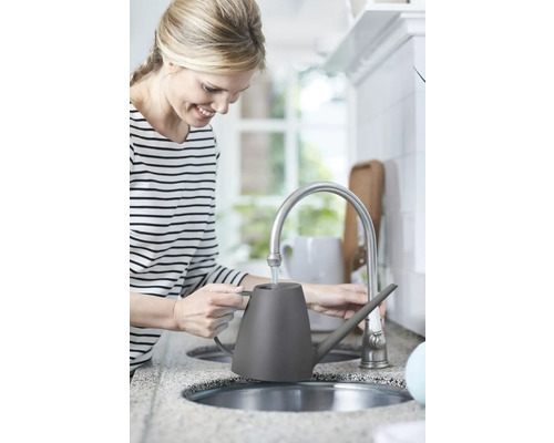 Vrouw vult een grijze gieter bij een waterkraan