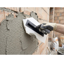 Een bakstenen muur pleisteren met een pleisterspaan