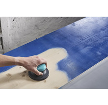 Een persoon schuurt een blauw houten oppervlak met een excentrische schuurmachine.