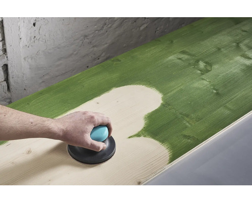 Iemand schuurt een groen geverfd houten oppervlak met een excentrische schuurmachine.