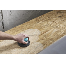 Een persoon schuurt een houten plaat met een handschuurmachine.