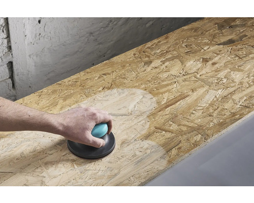 Een persoon schuurt een houten plaat met een handschuurmachine.