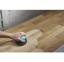 Iemand schuurt een houten blad met een excentrische schuurmachine.