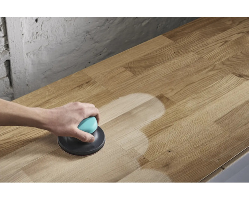 Iemand schuurt een houten blad met een excentrische schuurmachine.