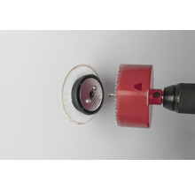 Boormachine met gatenzaag snijdt een gat in een muur