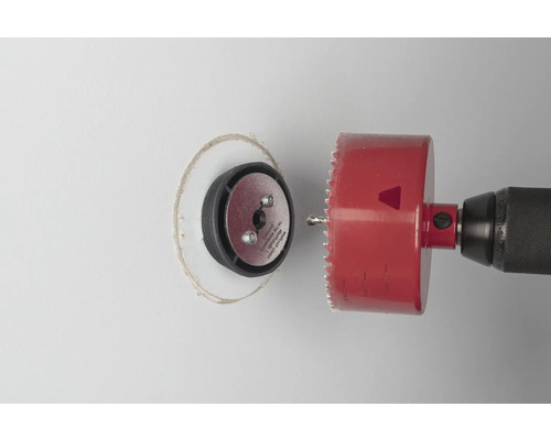 Boormachine met gatenzaag snijdt een gat in een muur