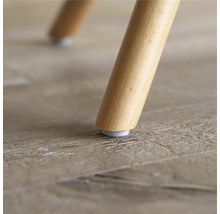 Close-up van een houten stoelpoot met vilten glijder op een houten vloer