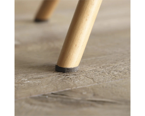 Detailopname van een stoelpoot met viltglijder op een houten vloer