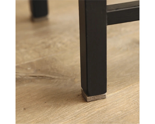 Detailopname van een zwarte meubelpoot met een vilten glijder ter bescherming van de vloer.