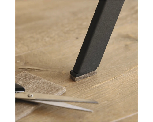 Viltglijder op een stoelpoot met schaar en stuk vilt op de vloer