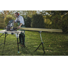 Ambachtsman zaagt hout met een verstekzaag op een zaagtafel in de tuin.