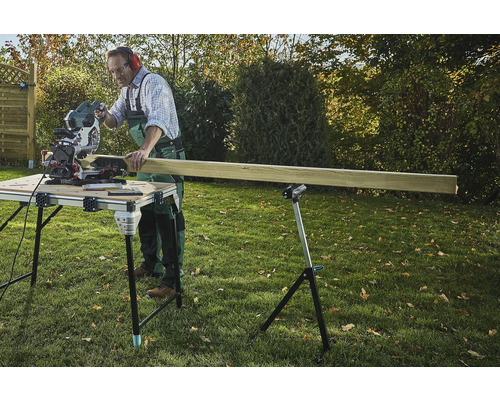 Ambachtsman zaagt hout met een verstekzaag op een zaagtafel in de tuin.
