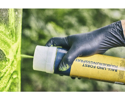 Een persoon met handschoenen gebruikt markeringsspray voor bouw en bos.