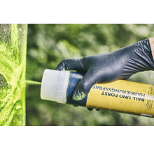 Een persoon met handschoenen gebruikt markeringsspray voor bouw en bos.