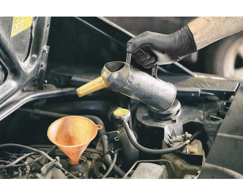 Motorolie wordt bijgevuld met trechter en oliekan
