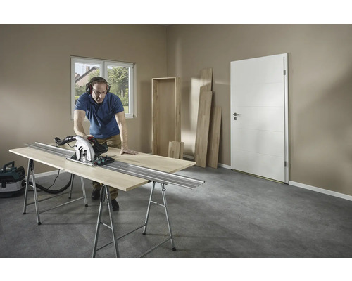 Man zaagt hout met een cirkelzaag op een werkbank in een kamer.