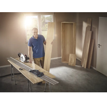 Man met cirkelzaag en geleiderail bij het zagen van hout voor een plank