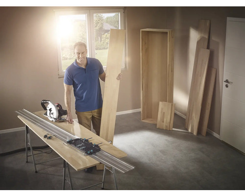 Man met cirkelzaag en geleiderail bij het zagen van hout voor een plank