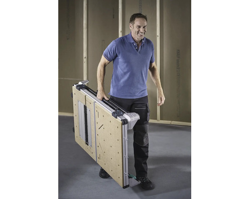 Een man draagt een ingeklapte werktafel.