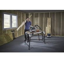 Man met houten balk, verstekzaag en werkbank in een casco.