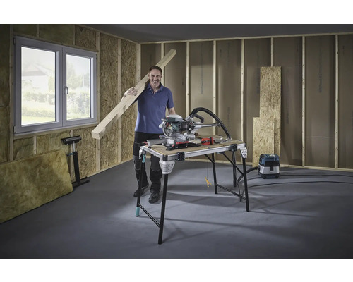 Man met houten balk, verstekzaag en werkbank in een casco.