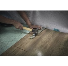 Persoon legt laminaat met trekijzer en hamer