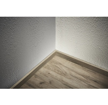 Hoek van een kamer met houten vloer en plint