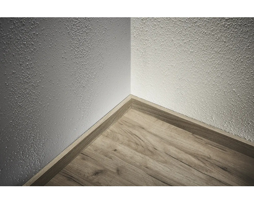 Hoek van een kamer met houten vloer en plint
