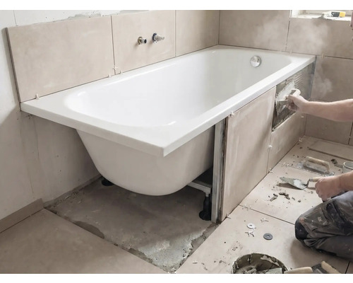 Installatie van een badkuip met tegels op de wanden en gereedschap in de badkamer.