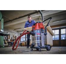 Werkplaatsopname met een Einhell nat-droogzuiger en een man die een houten plank bewerkt