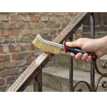 Een hand gebruikt een staalborstel voor metaalreiniging op een reling. Rautner Logo zichtbaar.