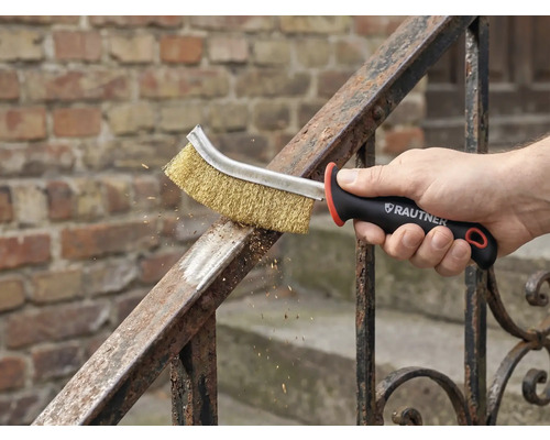 Een hand gebruikt een staalborstel voor metaalreiniging op een reling. Rautner Logo zichtbaar.