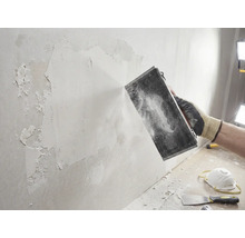 Ambachtsman schuurt muur met schuurwerktuig. Doe-het-zelfproject voor muurrenovatie.