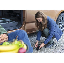 Vrouw bedient een elektrische luchtpomp naast een voertuig