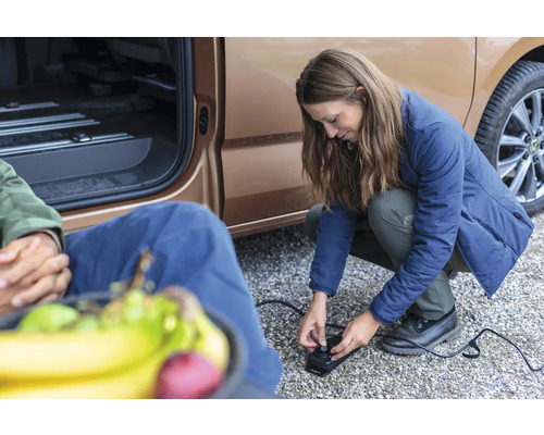 Vrouw bedient een elektrische luchtpomp naast een voertuig