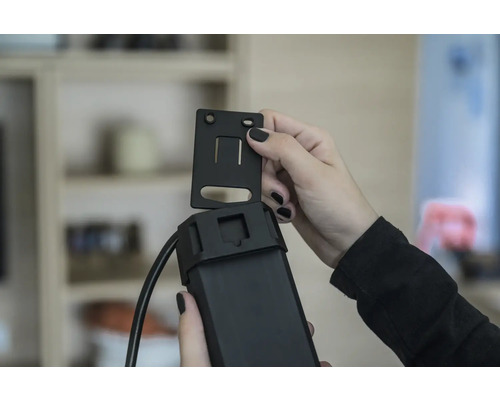 Een persoon bevestigt een beugel aan een elektronisch apparaat.