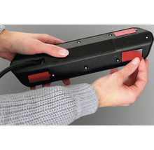 Iemand bevestigt een stekkerdoos met plakstrips.