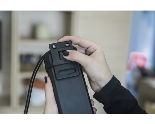 Een persoon bedient een zwarte kabelgoot.