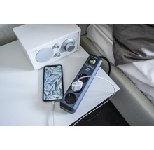 Verlengsnoer met overspanningsbeveiliging en aangesloten telefoon op een nachtkastje