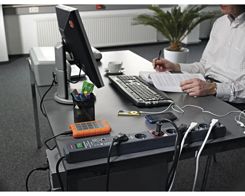 Werkplek met stekkerdoos, elektronische apparaten en persoon