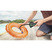 Een persoon pompt een zwemband op met een Bosch luchtpomp naast een zwembad.