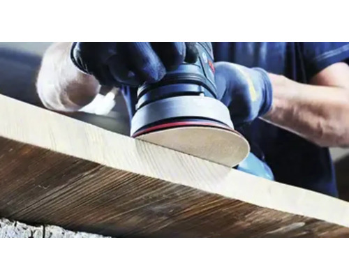 Iemand schuurt een houten plank met een excentrische schuurmachine.