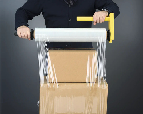Man verpakt dozen met een hand stretchfolie met handvat.