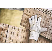 Een arbeider draagt bakstenen met handschoenen.