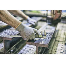 Een persoon meet een stuk metaal met een digitale schuifmaat op een ligger.