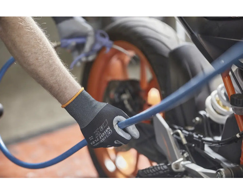 Iemand houdt een blauwe slang vast met een paar werkhandschoenen en maakt een motorfiets schoon.