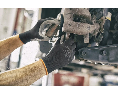 Monteurshanden werken aan een autorad met beschermende handschoenen.